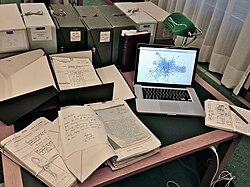 A laptop computer next to archival materials