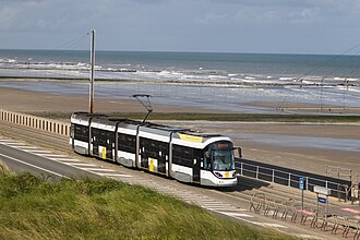 รถรางห้าตู้กำลังวิ่งบนรางระหว่างถนนและชายหาด